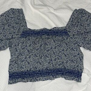 Blue smocked crop blouse with crew neck, cap sleeves, button back closure